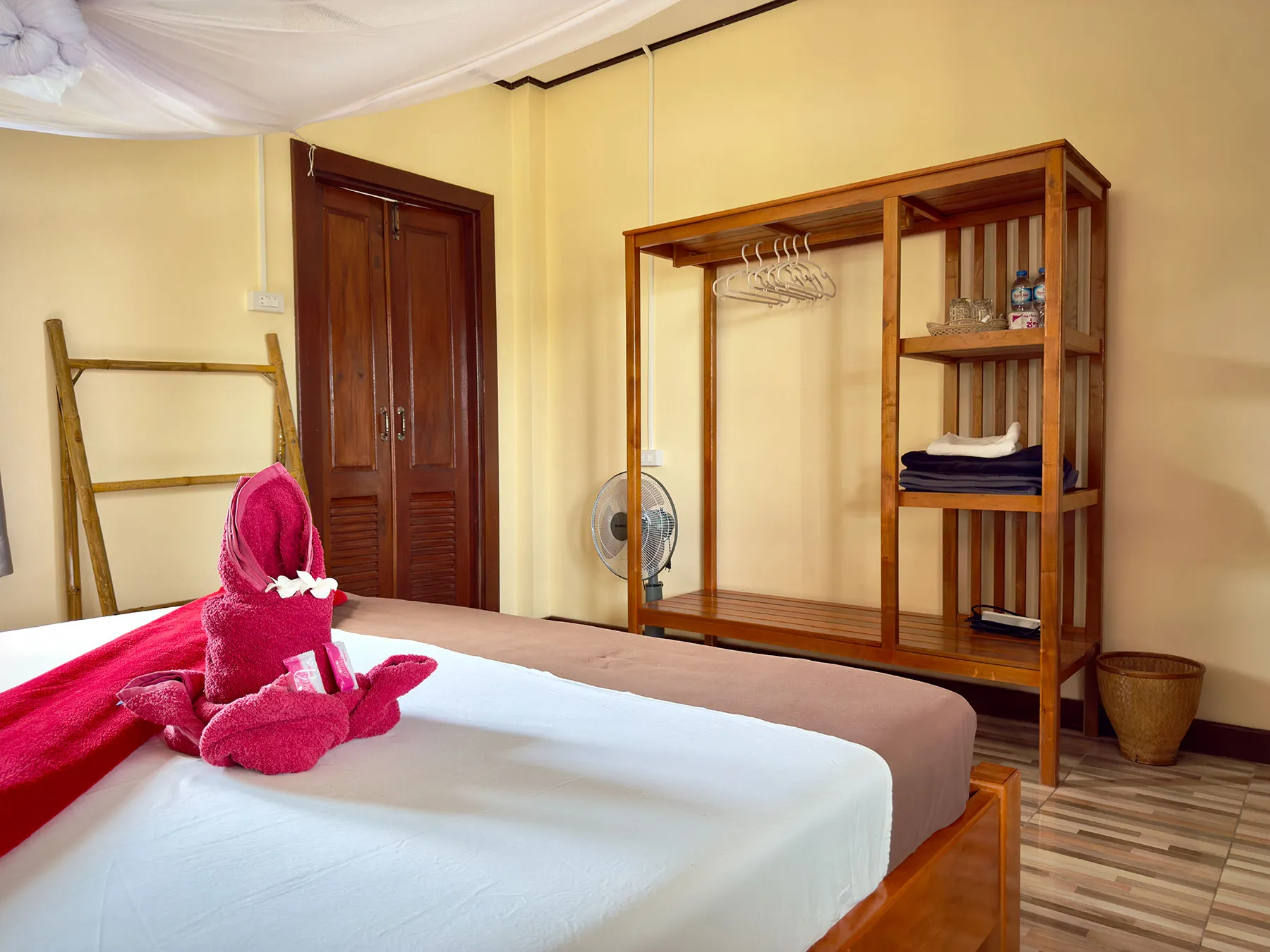 Riverfront Bungalow — Schlafzimmer mit Moskitonetz und Blick zur Veranda